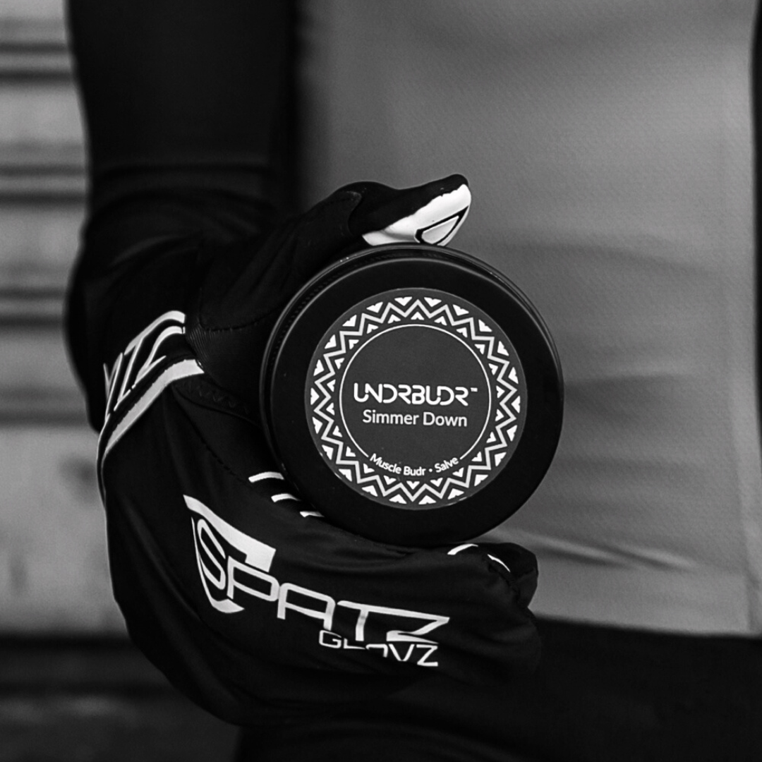 Female cyclist holding a tub of simmer down salve at her hip.